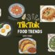 Infographic titled TikTok Food Trends: Worth Trying? featuring illustrations of viral recipes like the tortilla wrap hack, salmon rice bowl, Marry Me chicken, sleepy girl mocktail, pesto eggs, baked feta pasta, birria tacos, and green goddess salad.